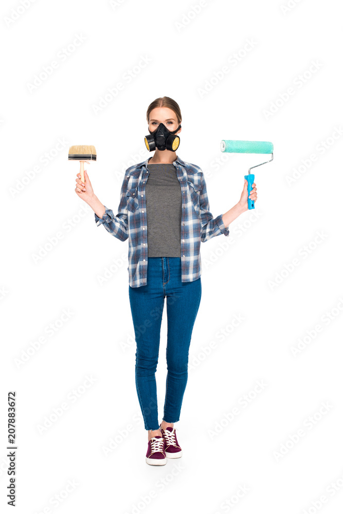 young woman in respirator holding paint brush and paint roller isolated on white background young woman in respirator holding paint brush and paint roller isolated on white background