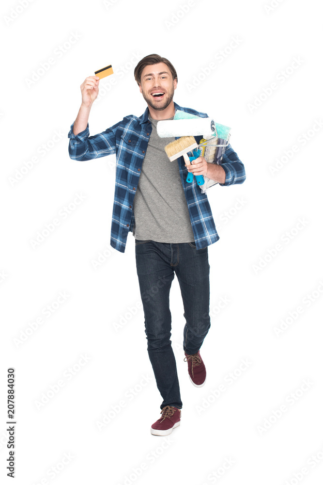 happy man with credit card holding paint rollers and paint brush isolated on white background happy man with credit card holding paint rollers and paint brush isolated on white background