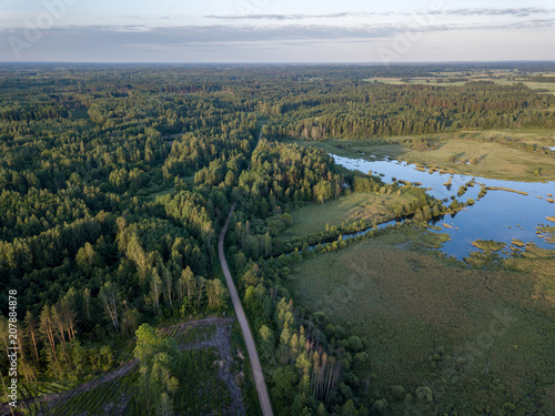 drone image. country lake surrounded by pine forest and fields from above © Martins Vanags