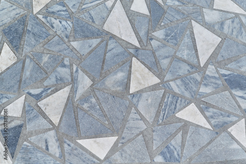 The surface of the floor or wall is made of marble tiles in the form of triangles. The surface is smooth and even. Triangular tiles of different size and color. Texture, background or backdrop.