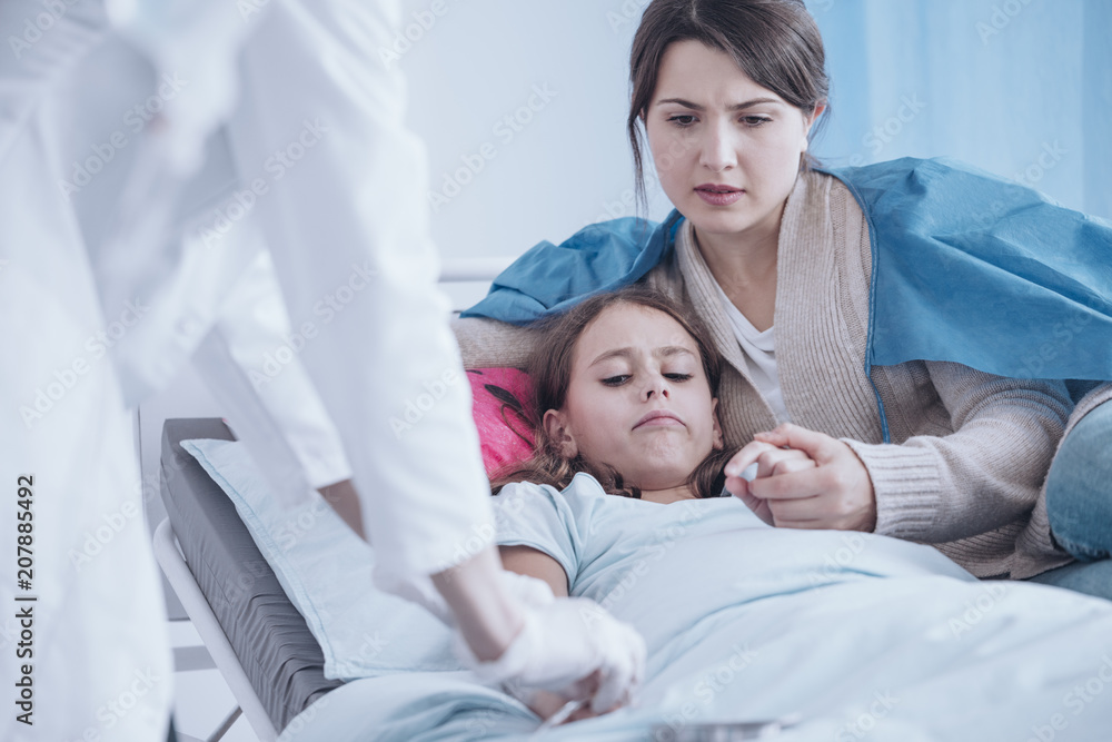 Mother supporting weak daughter while nurse establishing a venflon Mother supporting weak daughter while nurse establishing a venflon