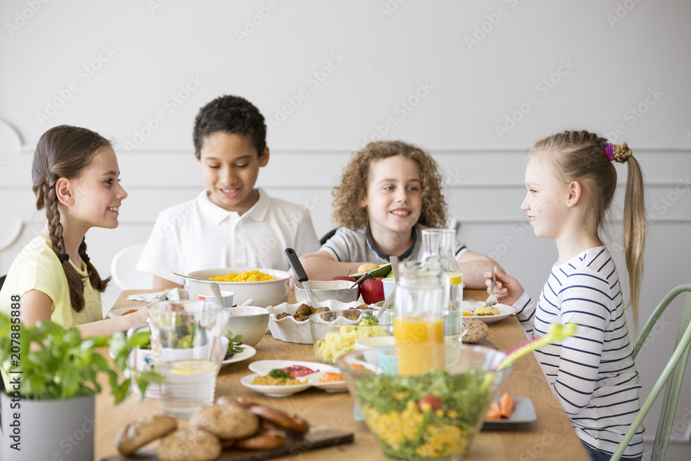 Smiling kids eating dinner while celebrating meeting at home Smiling kids eating dinner while celebrating meeting at home