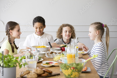 Smiling kids eating dinner while celebrating meeting at home