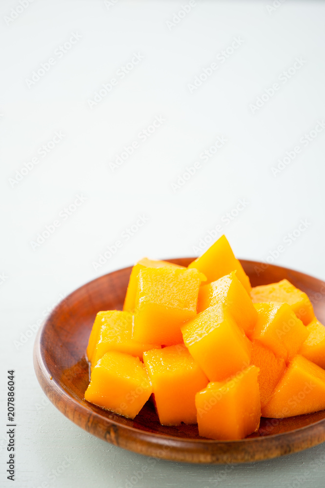 Fresh and beautiful mango fruit with sliced diced mango chunks on a light blue background, copy space(text space), blank for text. Fresh and beautiful mango fruit with sliced diced mango chunks on a light blue background, copy space(text space), blank for text.