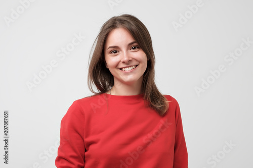 Portrait of young beautiful gcaucasian woman in red t-shirt cheerfuly smiling looking at camera. Studio photo isolated on white background. Copy space. photo