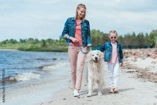 beautiful family walking with dog on sea shore