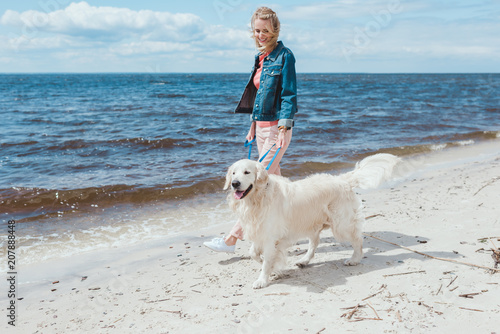 beautiful woman walking with golden retriever dog on sea shore © LIGHTFIELD STUDIOS
