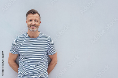 Friendly middle-aged man posing against a wall