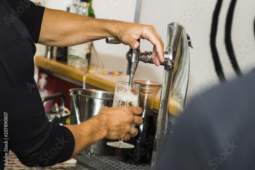 Bartender pouring fresh cold beer from tap