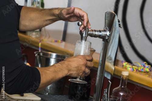 Bartender pouring fresh cold beer from tap
