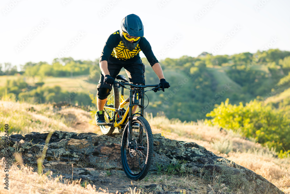 Cyclist Riding the Mountain Bike on the Summer Rocky Trail at the Evening. Extreme Sport and Enduro Cycling Concept. Cyclist Riding the Mountain Bike on the Summer Rocky Trail at the Evening. Extreme Sport and Enduro Cycling Concept.