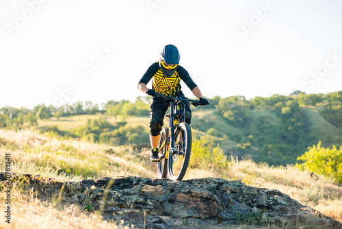 Cyclist Riding the Mountain Bike on the Summer Rocky Trail at the Evening. Extreme Sport and Enduro Cycling Concept.