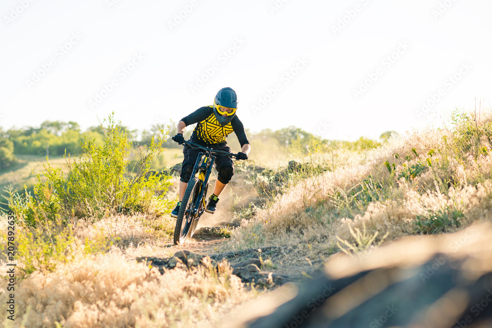 Obraz premium Cyclist Riding the Mountain Bike on the Summer Rocky Trail at the Evening. Extreme Sport and Enduro Cycling Concept.