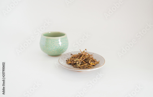 Dried tea with a cup of tea on a white background.