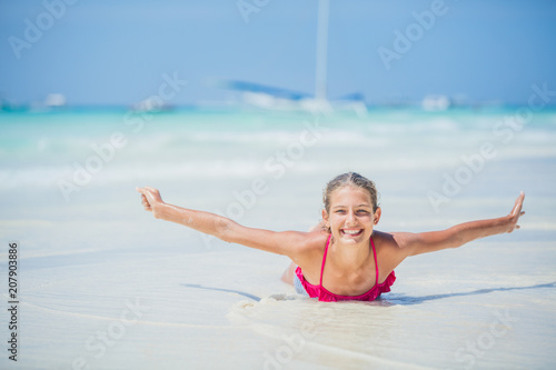Girl in bikini lying and having fun on tropical beach photo