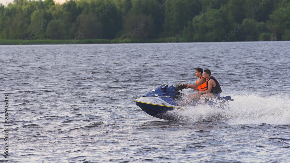 Fototapeta premium People riding on a jet ski. High speed jetski with water spray. People rid on water scooter.