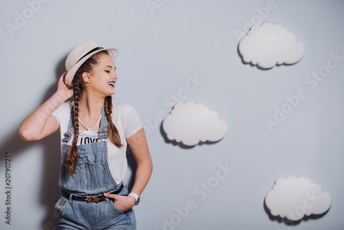 Girl in fashionable denim overalls.Stylish Urban Girl in shirt and Denim overalls.girl in a hat © ZoomStudio