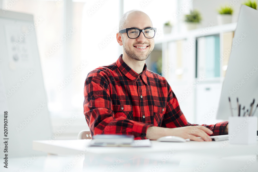 Portrait of casual businessman in eyeglasses sitting at his workplace at office Portrait of casual businessman in eyeglasses sitting at his workplace at office