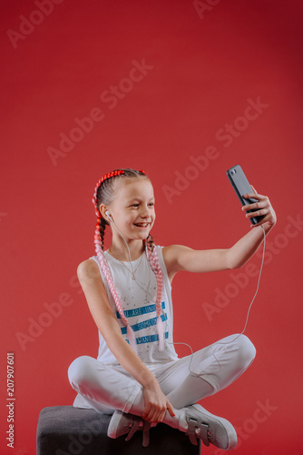 Adorable little girl taking a photo of herself with a smartphone.Beautiful little girl listening to music.The girl speaks to Skype with her friends