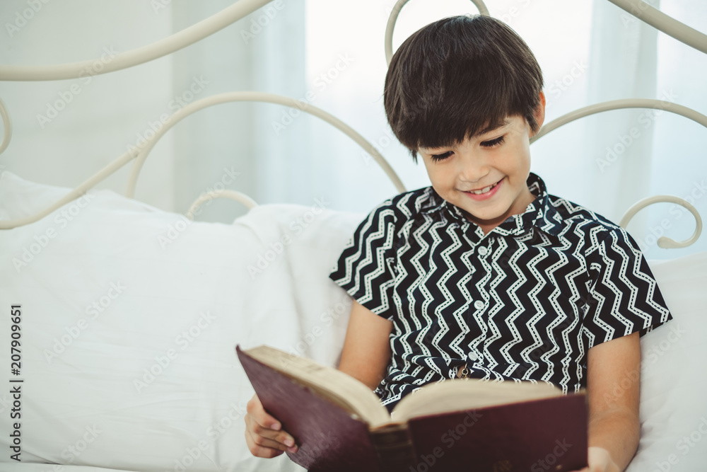 Boy reading book on white bed with smile and happy, lifestyle weekend