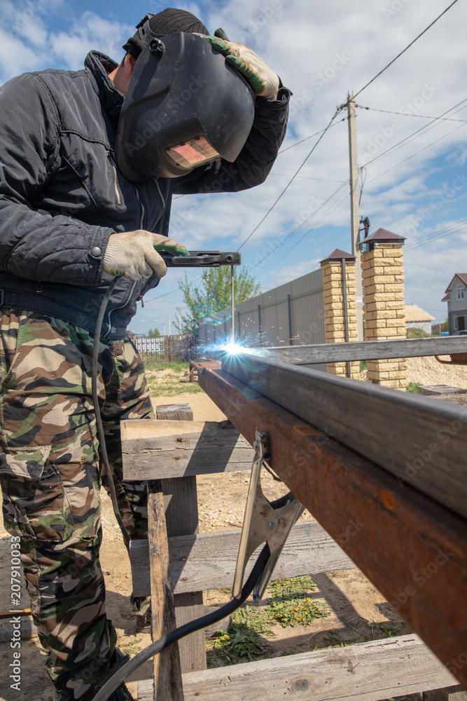Fototapeta premium Welder welds metal at the construction site