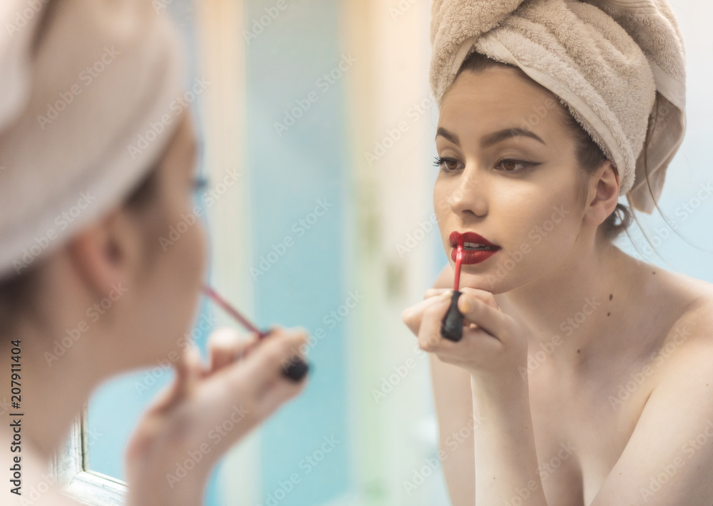 Foto Stock Close up of young woman applying lipstick in front of mirror |  Adobe Stock