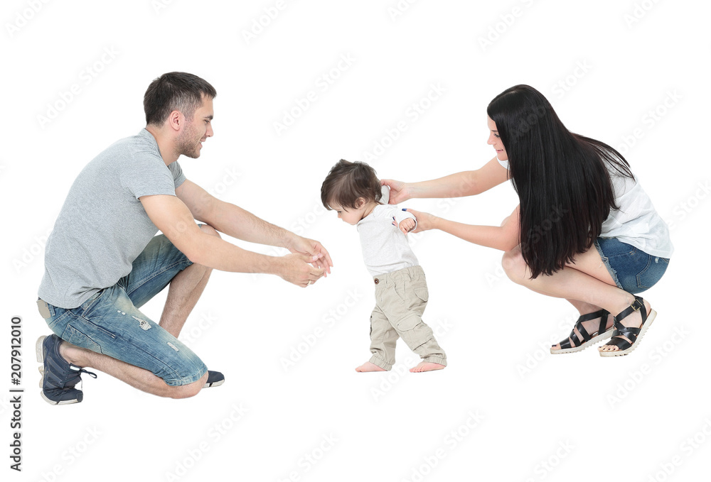 little boy making  first steps with the help of parents