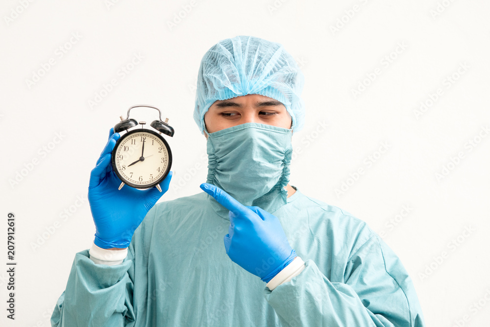 Portrait of a young surgeon with clock alarm over white background. Portrait of a young surgeon with clock alarm over white background.