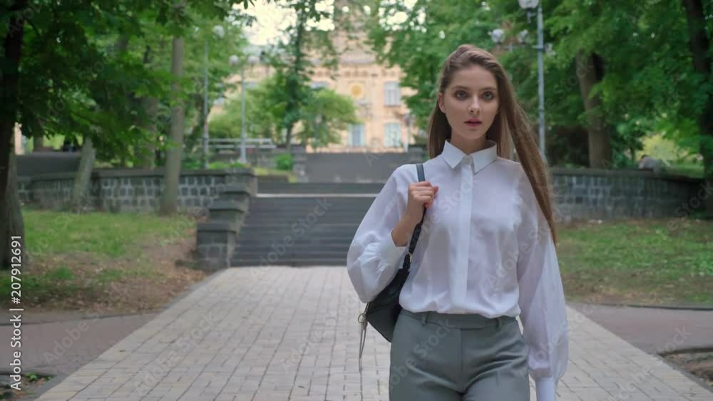 Young beautiful confident girl is going through park in daytime in summer, thinking conception Young beautiful confident girl is going through park in daytime in summer, thinking conception