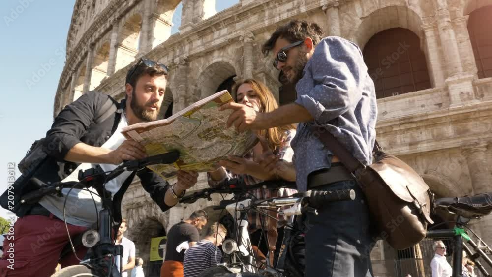 Three happy young friends tourists with bikes and backpacks at