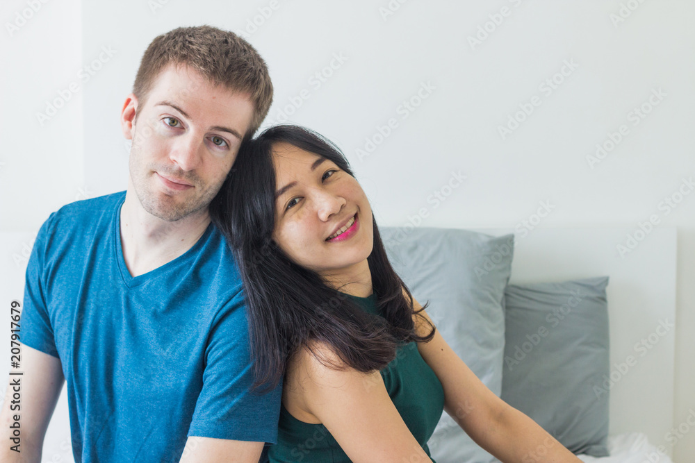 Couple with good communication skills.  White background laying on bed and happy.