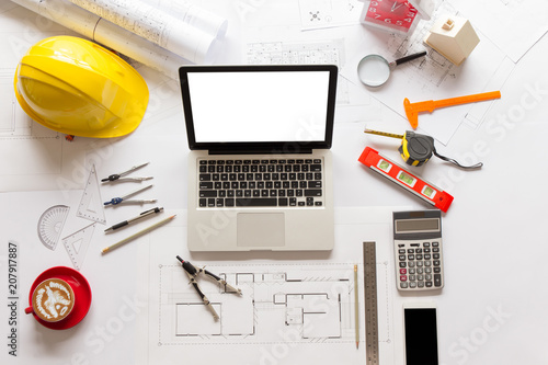 Top view of Blueprints, helmet, laptop, pencil, dividers, smartphone and engineer equipment on working desk.