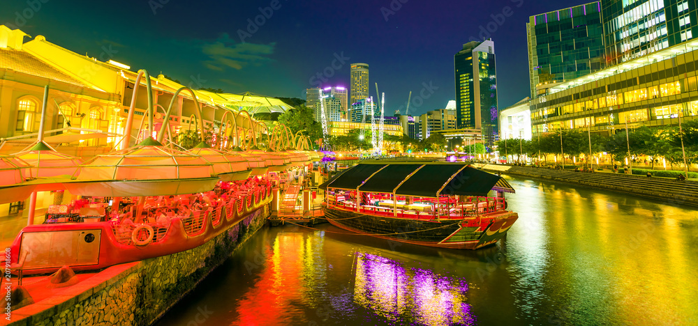 Naklejka premium Malowniczy obszar Clarke Quay Riverside z rejsem zacumowanym na molo w Singapurze, Azji Południowo-Wschodniej o zmierzchu. Waterfront skyline odzwierciedlenie na rzece Singapur. Popularna atrakcja nocnego życia.