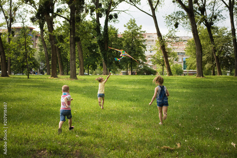 Rear view of children flying kite in nature.