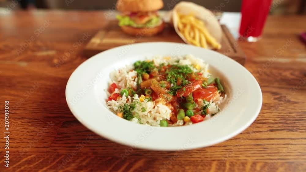 How thai rice with vegetables, burger and french fries on the table. How thai rice with vegetables, burger and french fries on the table.
