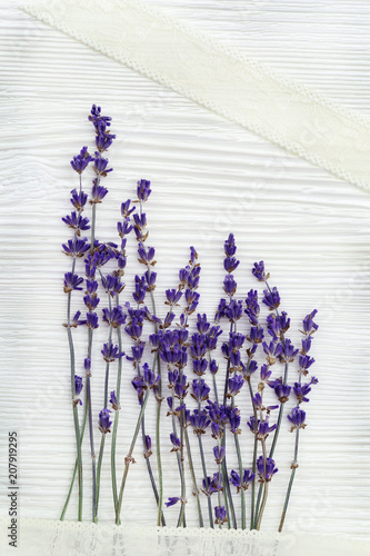 Small flowers of lavender with lace braid on white wood background with copy space. Top view. Provans style photography.