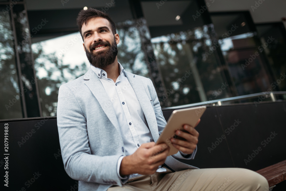 Shot of smiling businessman sitting on bench with digital tablet Shot of smiling businessman sitting on bench with digital tablet