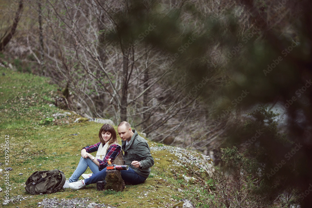 The guy with the girl in camp, roasting food on the fire. In the forest. The guy with the girl in camp, roasting food on the fire. In the forest.