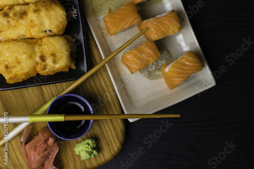 mix of sushi with cheese, salmon, shrimps, avokado, cucumber. Japan food with chopsticks, ginger, wasabi, soy souce on wooden board photo