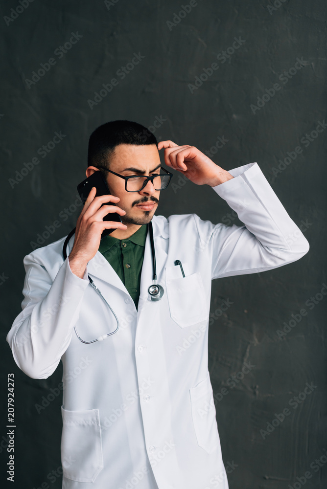 Smiling medical doctor calling by phone. Smiling medical doctor calling by phone.