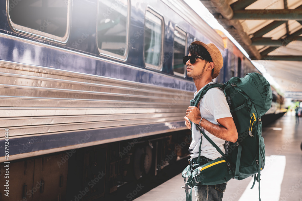 Young asian traveler with backpack in the railway, Backpack and hat at the train station with a traveler, Travel concept
