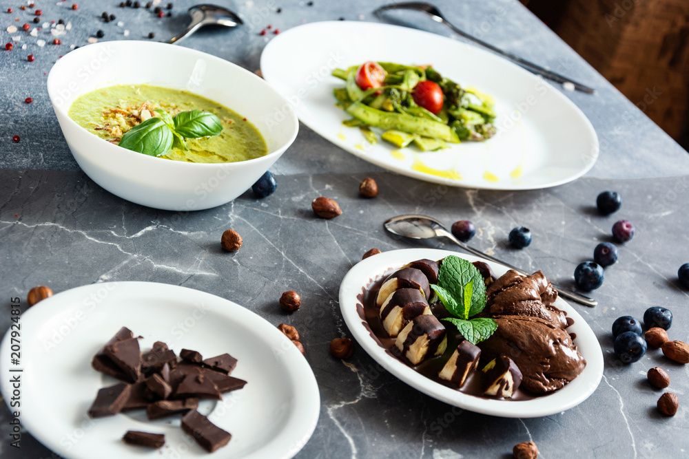 vegetarian food, green cream soup, sala with asparagus and cherry tometoes, banana and vegan chocolate ice cream