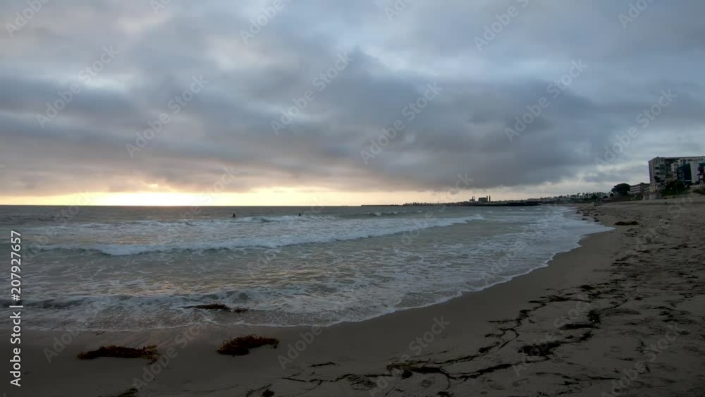 Slow pan from sea shore hotels across the ocean to a man made rocky pier in a yellow sunrise on a cloudy day Slow pan from sea shore hotels across the ocean to a man made rocky pier in a yellow sunrise on a cloudy day