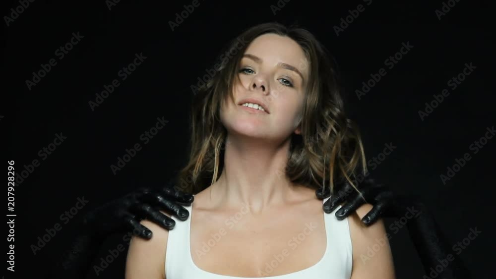 Black anonymous hands , symbolizing violence indicate to victim woman how to behave , the girl raised her chin, makes a synthetic smile, look to the camera Black anonymous hands , symbolizing violence indicate to victim woman how to behave , the girl raised her chin, makes a synthetic smile, look to the camera