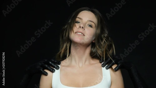 Black anonymous hands , symbolizing violence indicate to victim woman how to behave , the girl raised her chin, makes a synthetic smile, look to the camera