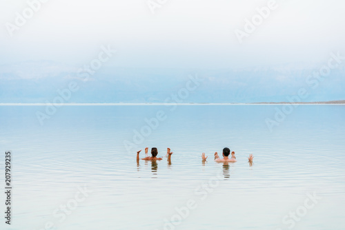 Young couple floating on surface of Dead Sea water and enjoying summer sun and vacation. Recreation tourism, healthy lifestyle, free time concept #207929235