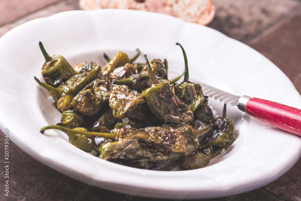 Green Padron Peppers with Olive Oil in Rustic White Plate. Pimientos de Padron. Green Padron Peppers with Olive Oil in Rustic White Plate. Pimientos de Padron.