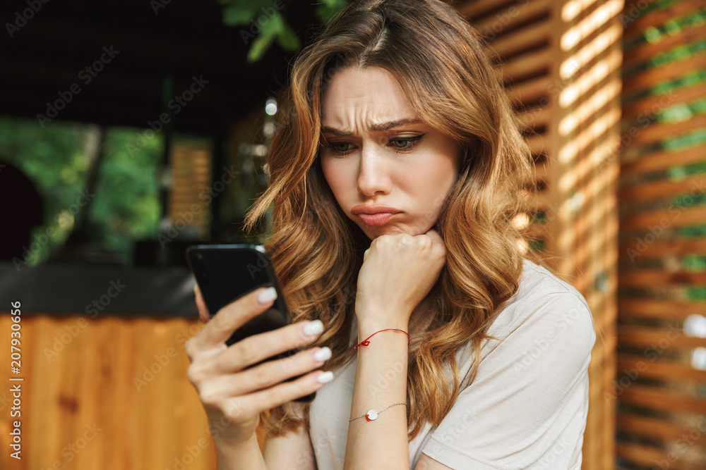 Portrait of a sad young girl looking at mobile phone Portrait of a sad young girl looking at mobile phone