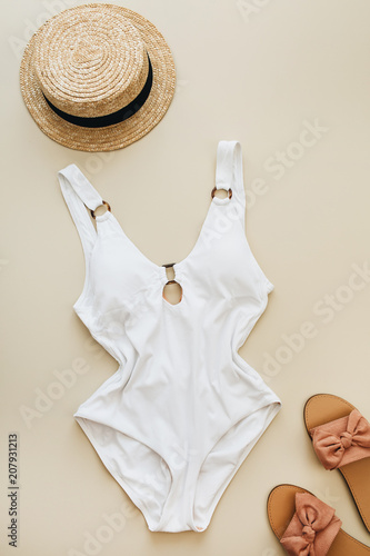 Flat lay summer fashion composition. Women's swimsuit, straw and slippers on pastel beige background. Flat lay, top view minimal beach concept.