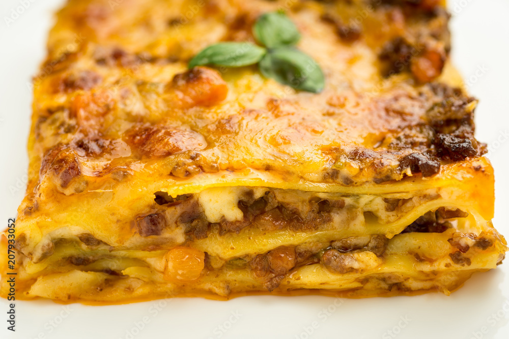 Italian Lasagna with Minced Beef, Bolognese Sauce and Basil on White Plate